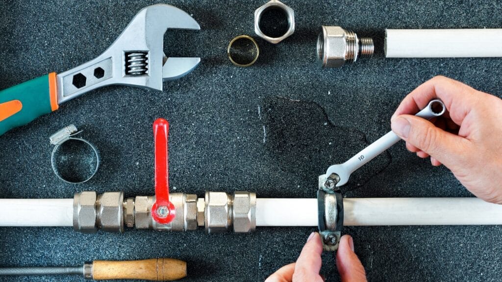 Plumber repairing a pipe valve with an adjustable wrench in Highland