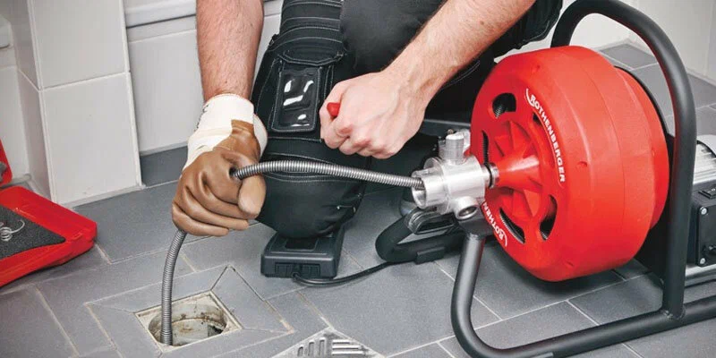 Plumber using a drain-cleaning machine in Highland