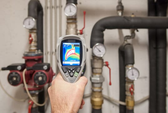 Plumber using a thermal imaging camera to inspect pipes in Highland